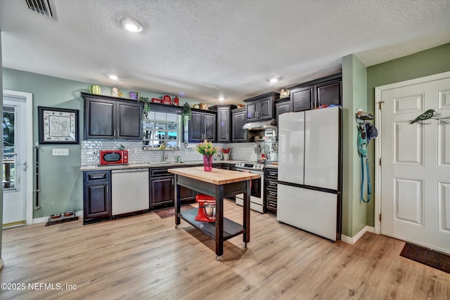 kitchen featuring light wood finished floors, visible vents, backsplash, appliances with stainless steel finishes, and a sink