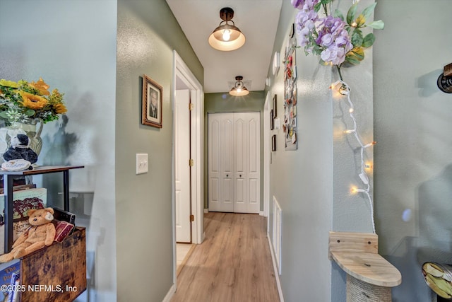 hallway with baseboards, visible vents, and light wood-style floors