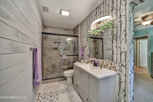 full bathroom featuring a stall shower, visible vents, toilet, a textured ceiling, and vanity