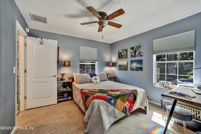 bedroom with a textured ceiling, ceiling fan, carpet, and visible vents