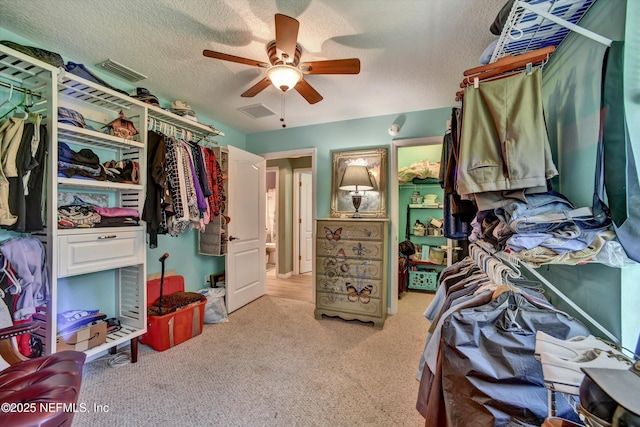 spacious closet featuring a ceiling fan, light colored carpet, and visible vents