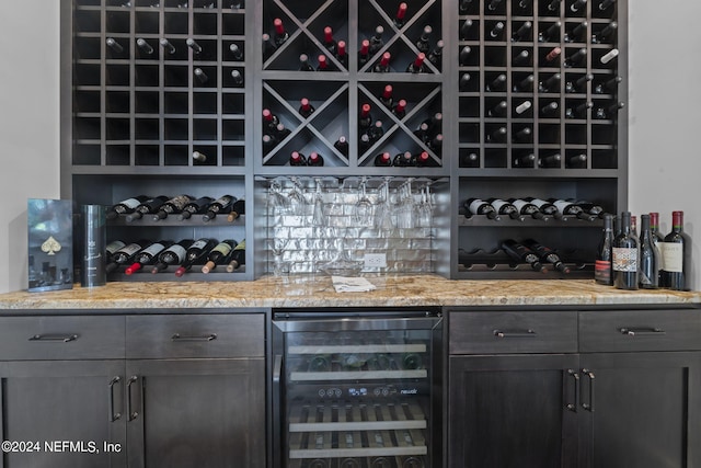 wine room featuring wine cooler and a bar