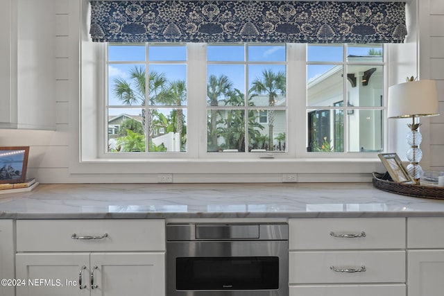 details featuring light stone counters, oven, and white cabinetry