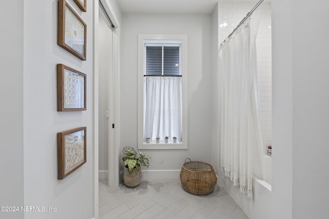 interior space with shower / bathtub combination with curtain and baseboards