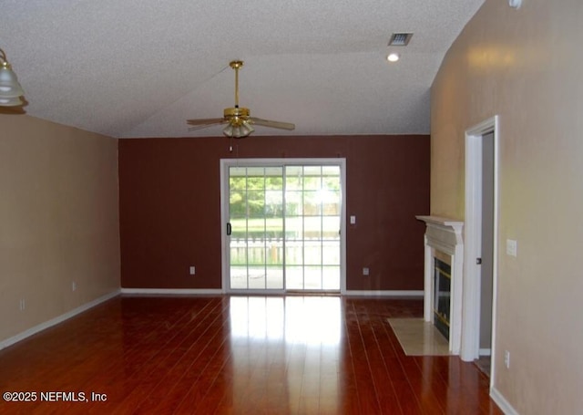 unfurnished living room featuring baseboards, visible vents, lofted ceiling, a fireplace with flush hearth, and wood finished floors