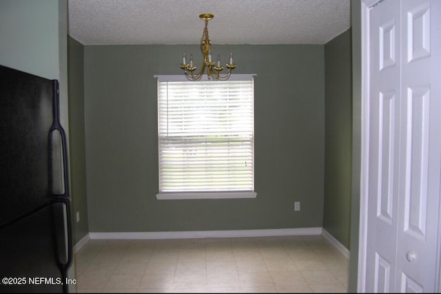 unfurnished dining area with a textured ceiling, baseboards, and a notable chandelier