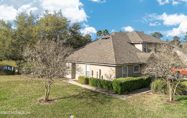 view of home's exterior with a yard, roof with shingles, and stucco siding