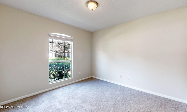 unfurnished room with carpet floors, baseboards, and a textured ceiling