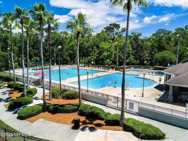 community pool with a patio area and fence