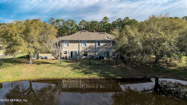 rear view of property with a lawn and a water view