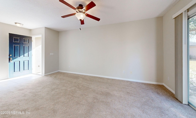 empty room featuring ceiling fan, baseboards, a textured ceiling, and light colored carpet