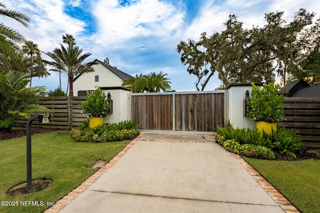 view of gate with a storage shed, fence, a lawn, and an outdoor structure