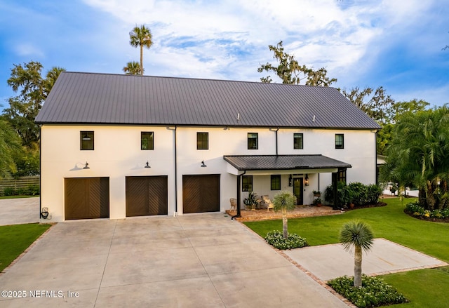 modern farmhouse featuring metal roof, a front lawn, concrete driveway, and stucco siding