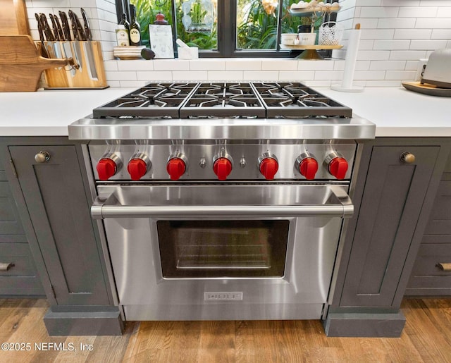 details featuring light wood-style flooring, designer stove, and backsplash