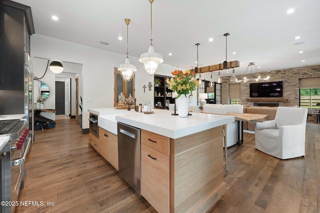 kitchen featuring stainless steel appliances, dark wood-style flooring, light countertops, and open floor plan