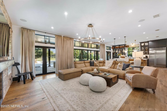 living area with a chandelier, light wood-style flooring, recessed lighting, visible vents, and french doors