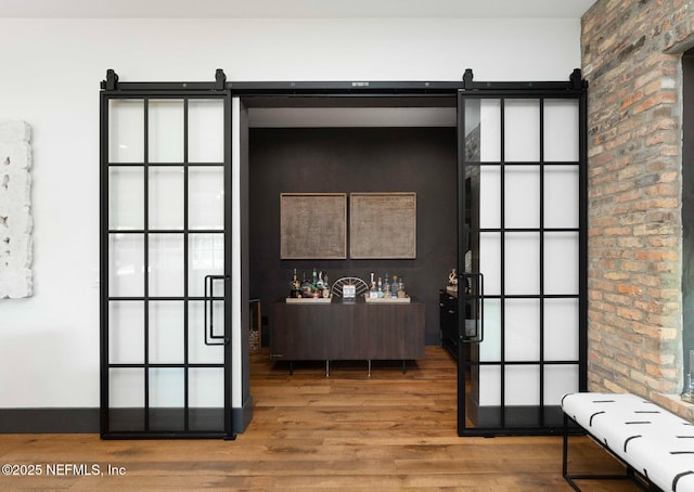 interior space with a barn door, wood finished floors, and baseboards