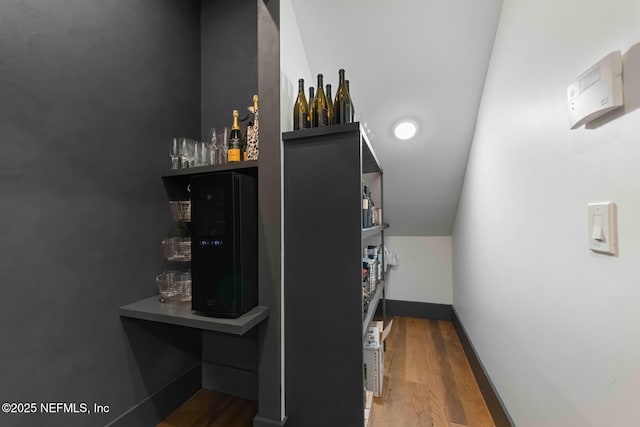 bar featuring vaulted ceiling, wood finished floors, and baseboards