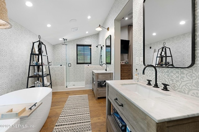 bathroom featuring wallpapered walls, a shower stall, a sink, and wood finished floors