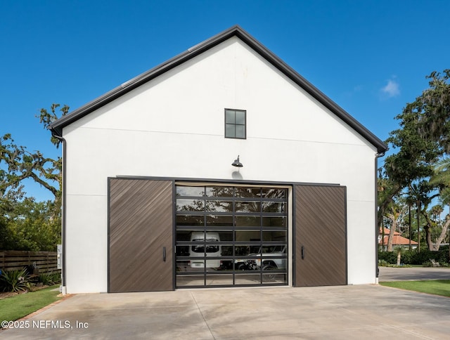 view of property exterior featuring stucco siding, a detached garage, fence, and an outdoor structure