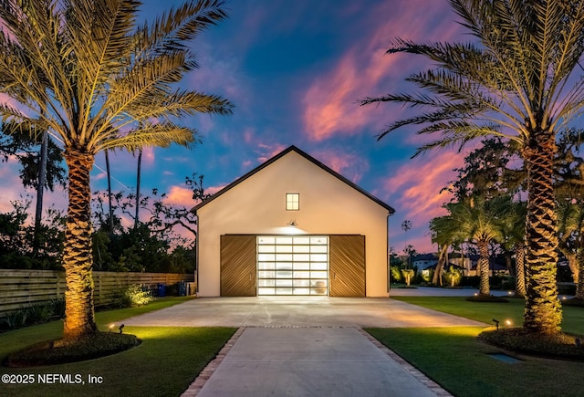 view of front of house featuring a garage, an outdoor structure, fence, a lawn, and stucco siding