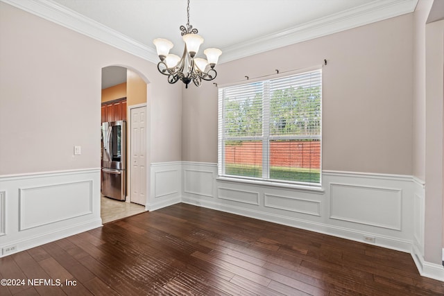 unfurnished dining area with arched walkways, a wainscoted wall, hardwood / wood-style flooring, and an inviting chandelier