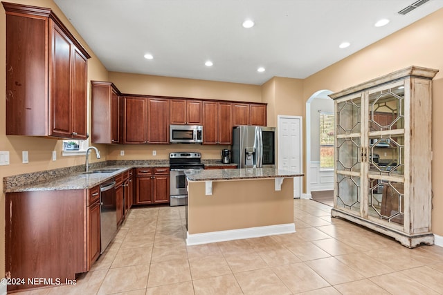 kitchen with arched walkways, a sink, visible vents, appliances with stainless steel finishes, and a center island