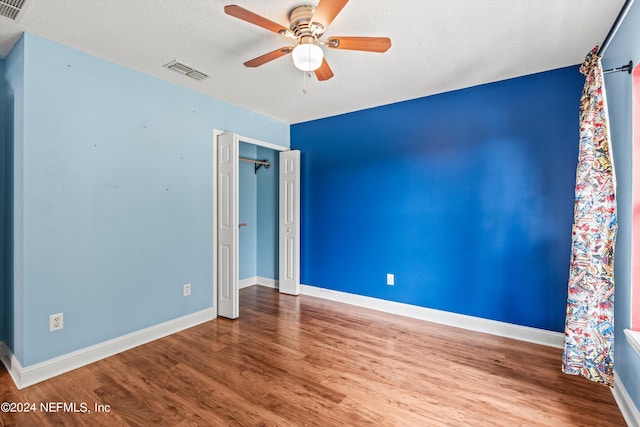 spare room with baseboards, visible vents, a ceiling fan, wood finished floors, and a textured ceiling