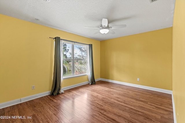 spare room featuring ceiling fan, a textured ceiling, baseboards, and wood finished floors