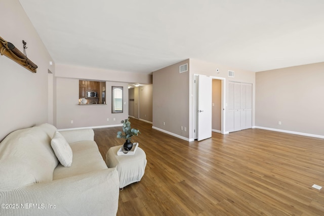 living room with wood finished floors, visible vents, and baseboards