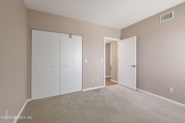 unfurnished bedroom with carpet flooring, baseboards, visible vents, and a closet