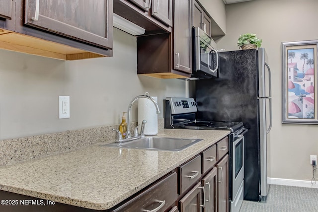 kitchen featuring a sink, dark brown cabinets, baseboards, and stainless steel appliances