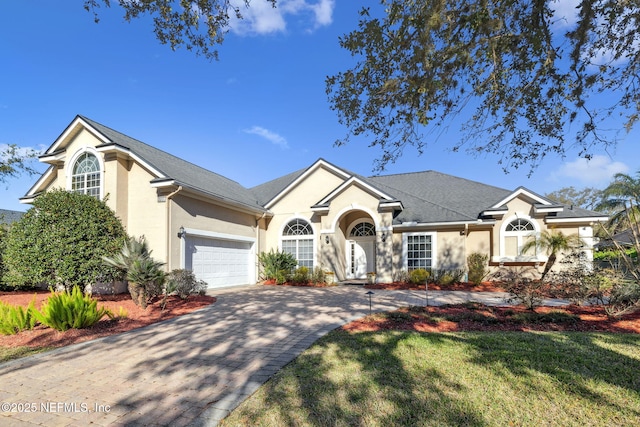 single story home with decorative driveway, an attached garage, and stucco siding