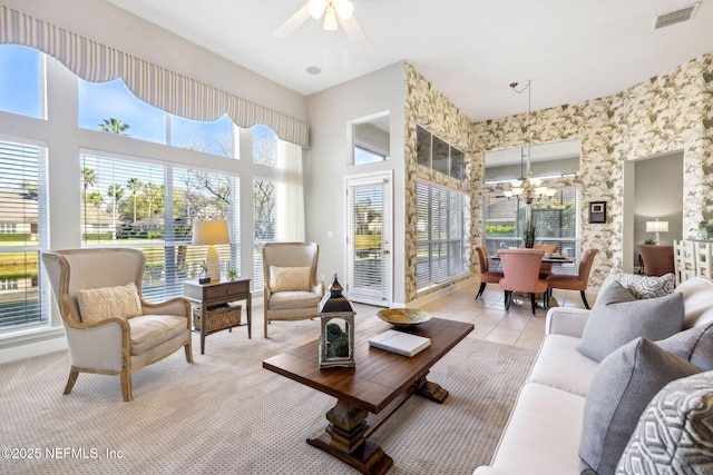 sunroom / solarium featuring ceiling fan with notable chandelier, visible vents, and a healthy amount of sunlight