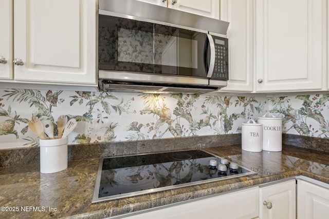 kitchen with dark countertops, white cabinetry, stainless steel microwave, and black electric cooktop