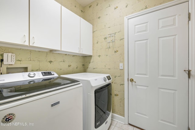 washroom with light tile patterned flooring, washing machine and dryer, and cabinet space