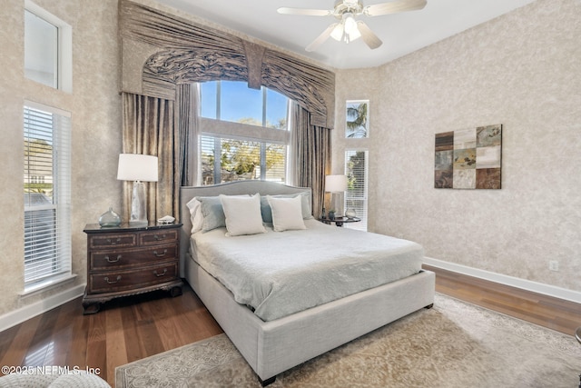 bedroom with ceiling fan, a high ceiling, baseboards, and wood finished floors