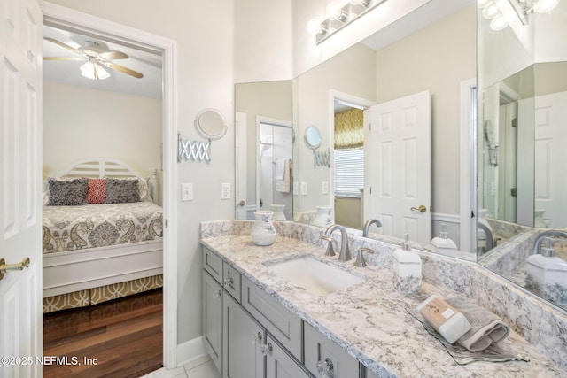 ensuite bathroom featuring baseboards, ensuite bath, vanity, and a ceiling fan