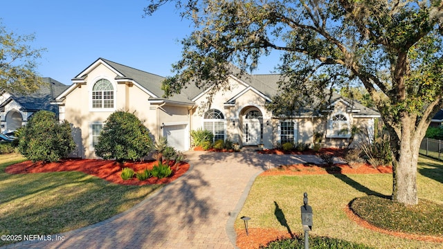 view of front of property with a garage, a front lawn, decorative driveway, and stucco siding