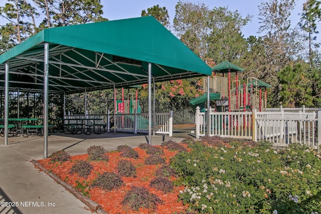 view of home's community with playground community, fence, and a detached carport