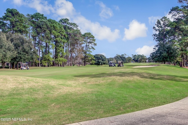 view of property's community with view of golf course and a lawn