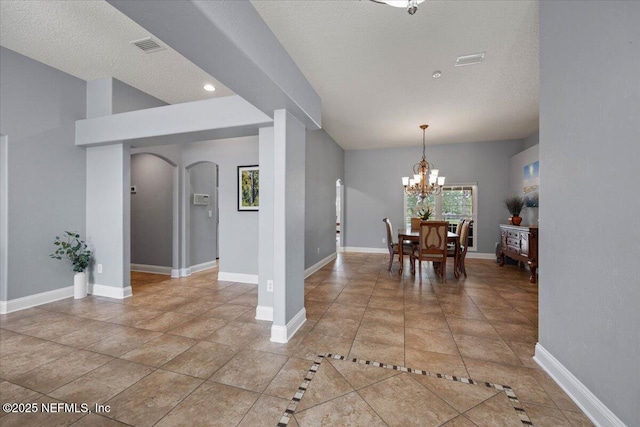 dining space featuring an inviting chandelier, baseboards, arched walkways, and a textured ceiling