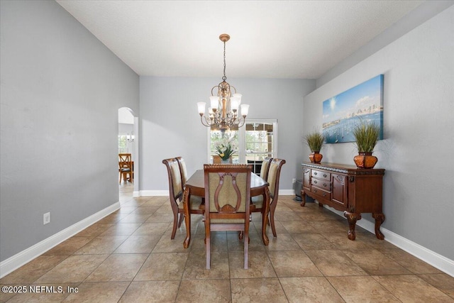 dining room featuring arched walkways, baseboards, and an inviting chandelier