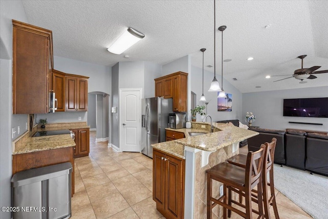 kitchen with a peninsula, light stone countertops, arched walkways, and a sink