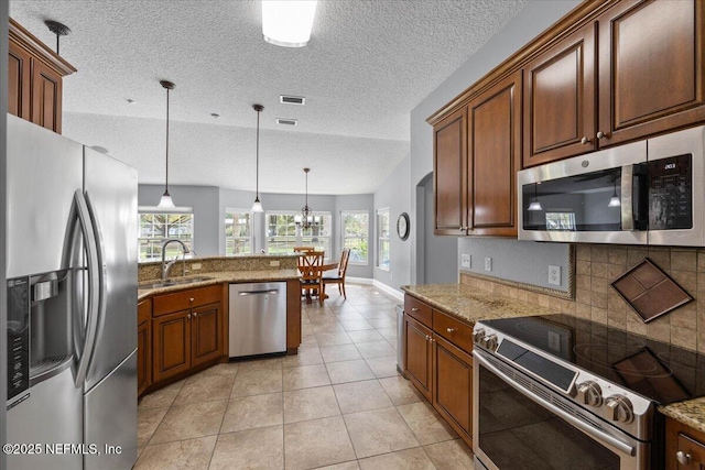 kitchen featuring tasteful backsplash, appliances with stainless steel finishes, hanging light fixtures, a sink, and light tile patterned flooring