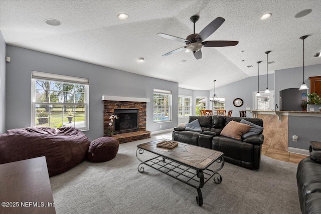 living room featuring carpet flooring, vaulted ceiling, a stone fireplace, and a textured ceiling