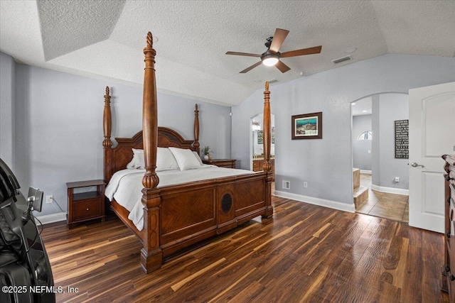 bedroom with visible vents, arched walkways, wood finished floors, vaulted ceiling, and a textured ceiling