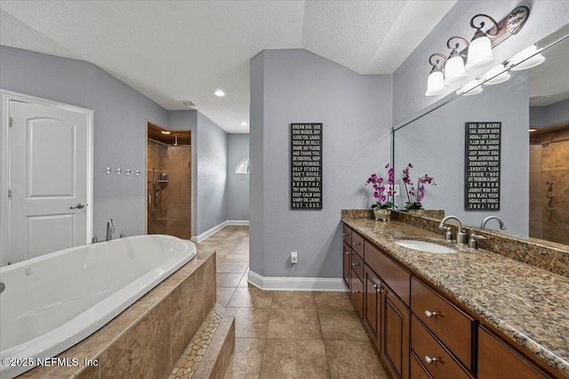 bathroom featuring lofted ceiling, a textured ceiling, vanity, and tiled bath