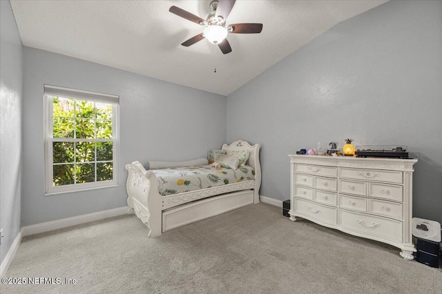 bedroom featuring ceiling fan, a textured ceiling, light colored carpet, baseboards, and vaulted ceiling