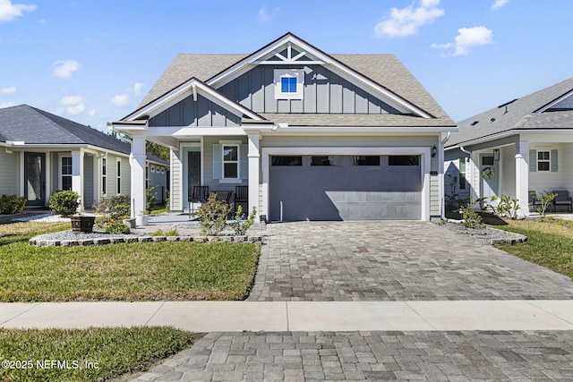 view of front facade featuring a garage, decorative driveway, board and batten siding, and roof with shingles